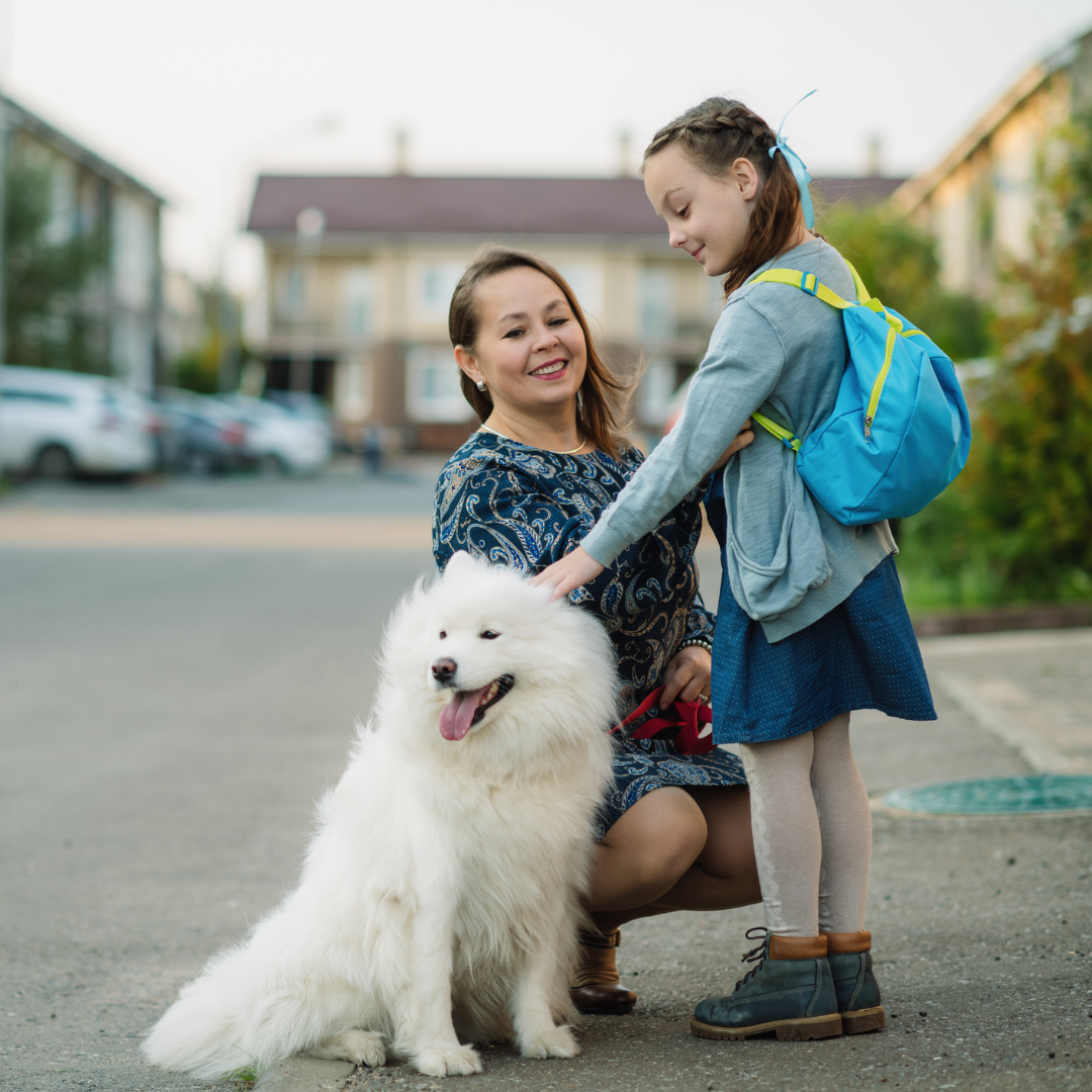 Mother picking daughter up from school with dog