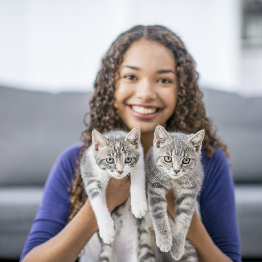 Teen girl holding two kittens